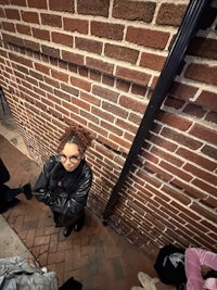 a woman standing in front of a brick wall